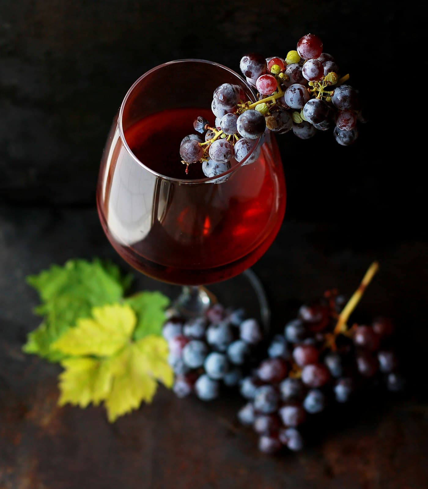 Copa de vino tinto con uvas sobre fondo oscuro