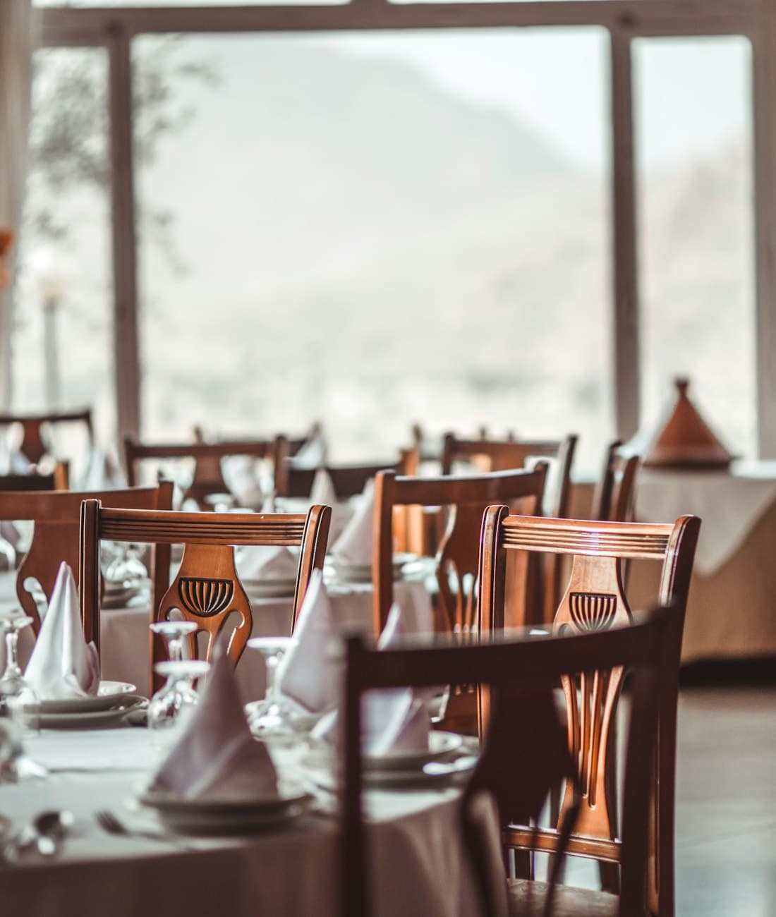 Salón con mesas vestidas de blanco y luz del atardecer