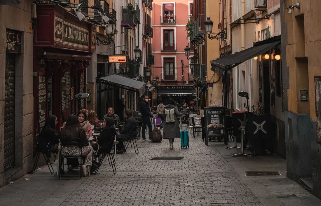 Calle empedrada del casco viejo de Madrid con terrazas y toldos a ambos lados