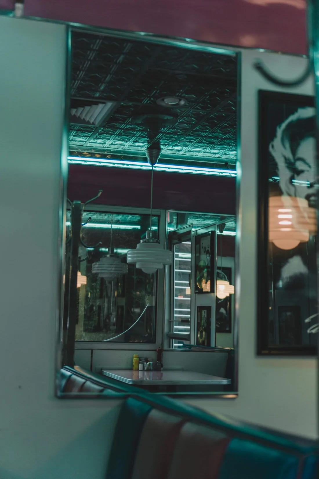 Interior del local con luz de neón turquesa, techo de chapa repujada y banco de skay