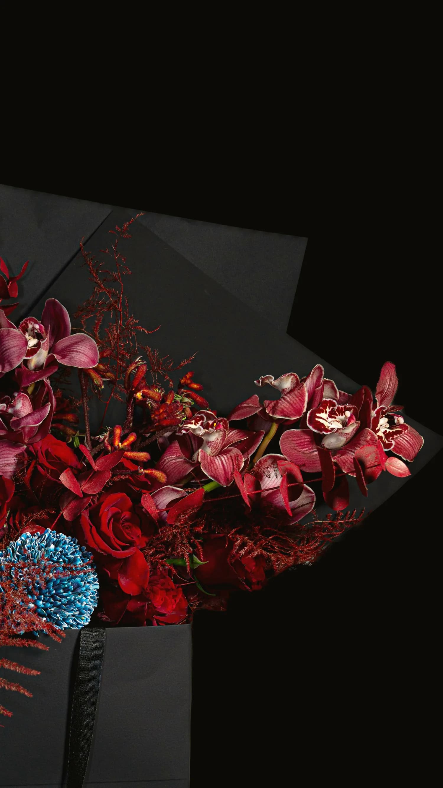 Ramo escultórico de flores raras sobre fondo oscuro