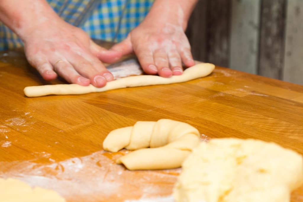 Manos dando forma a masa de hojaldre sobre la mesa de trabajo