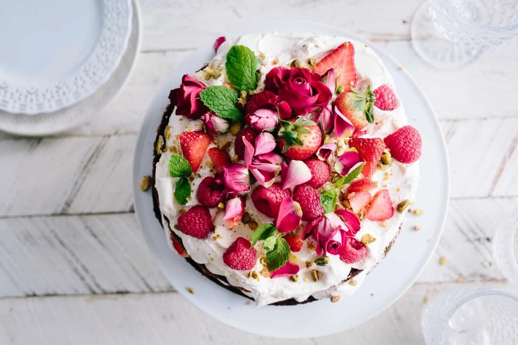 Pavlova cubierta de frambuesas, fresas y pétalos