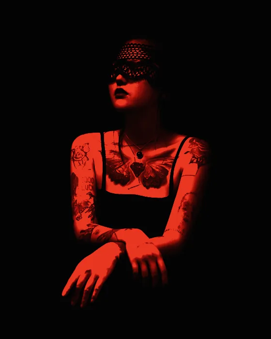 Retrato de Nuria Valls sentada sobre fondo negro, brazos tatuados y velo de encaje sobre los ojos